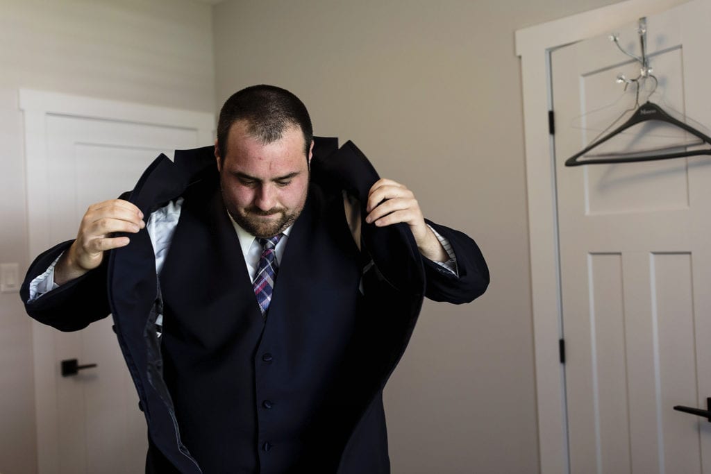 groom puts on jacket for navy suit