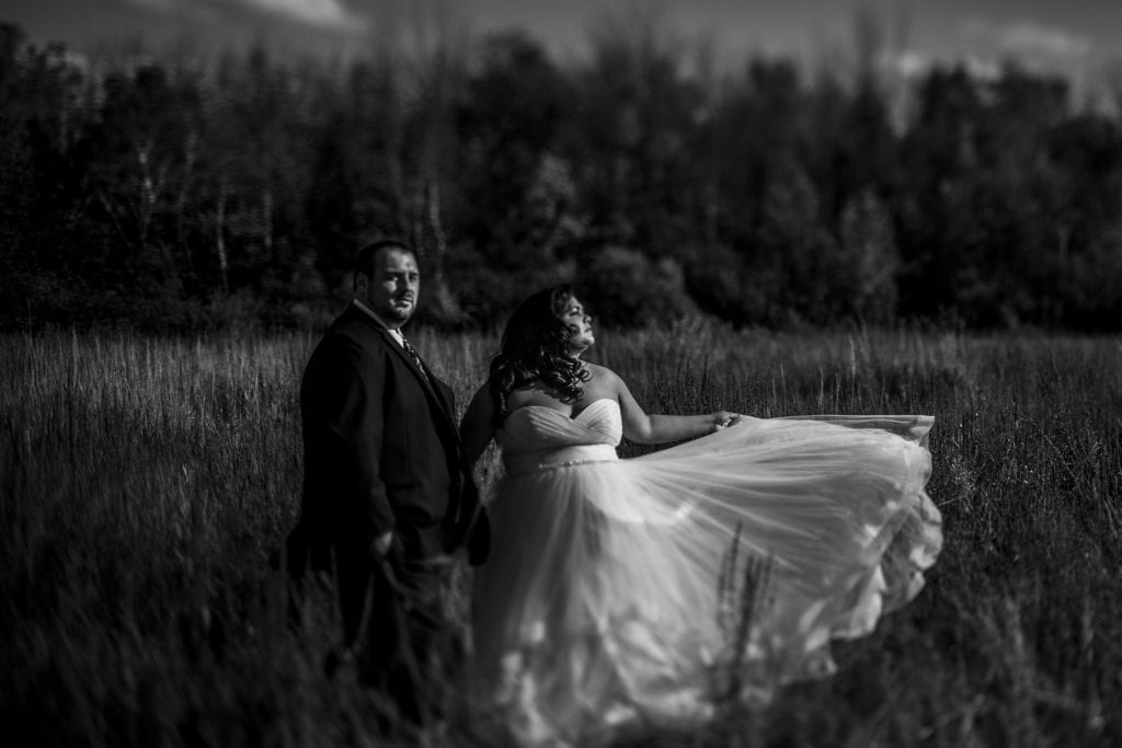 bride looks to sun and waves dress while groom looks away