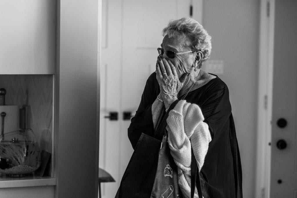 grandmother holds hands against mouth and looks emotional