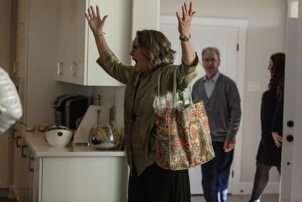woman looks shocked and throws hands in air as other guests enter house