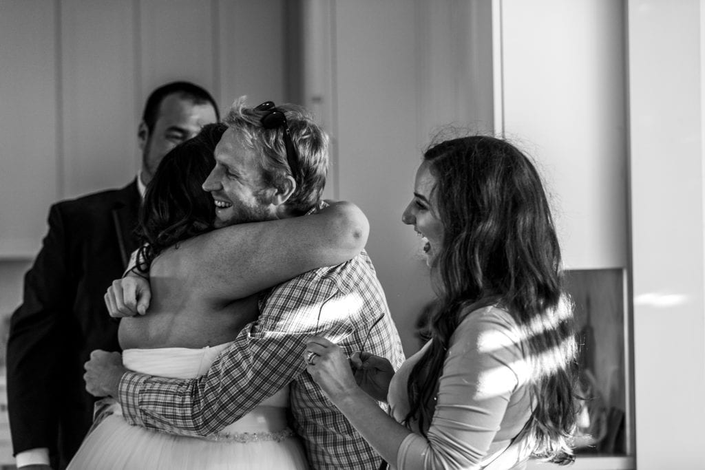 bride is hugged by surprised friends