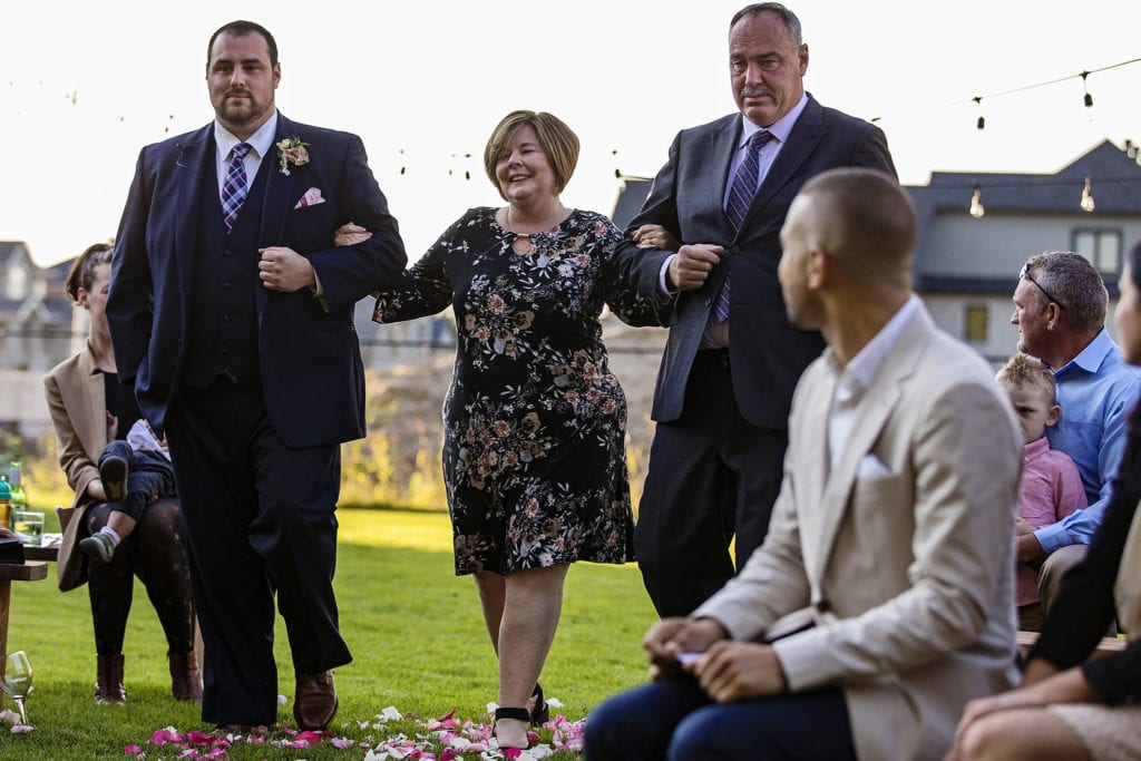 groom walks down aisle with mother and crying father