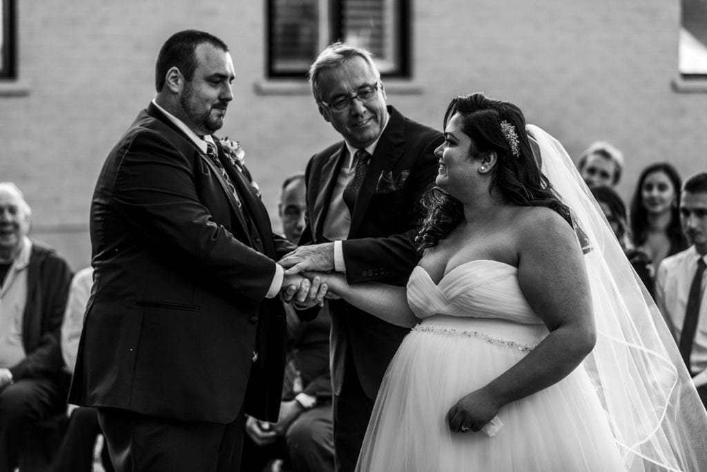 bride meets groom and uncle places her hand in groom's