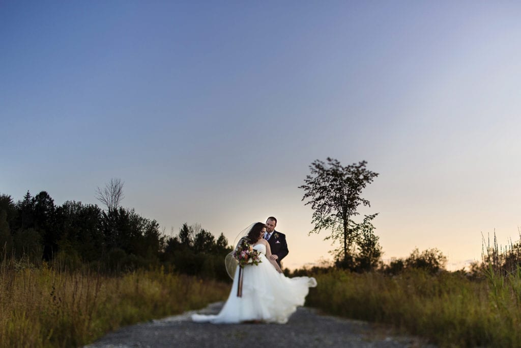 bride swishes dress while groom stands close