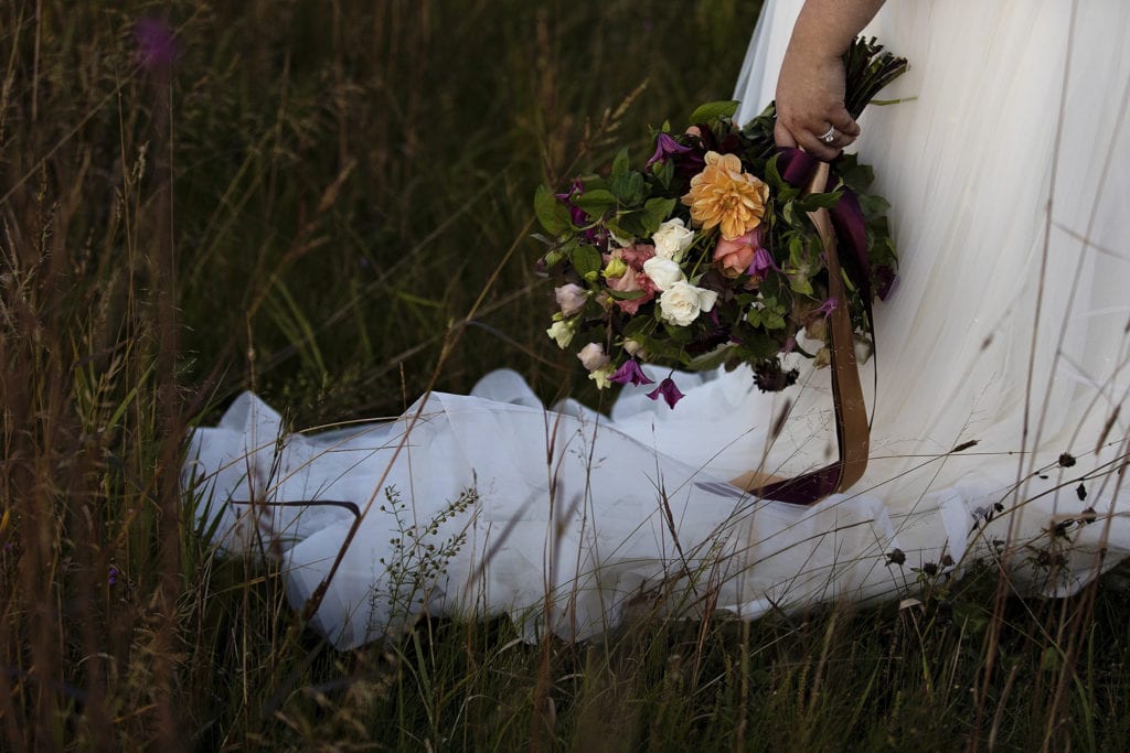 bride holds bouquet full of antique-toned florals against tulle dress