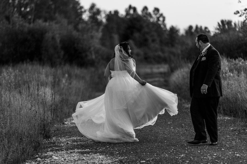 bride swishes dress as groom looks on