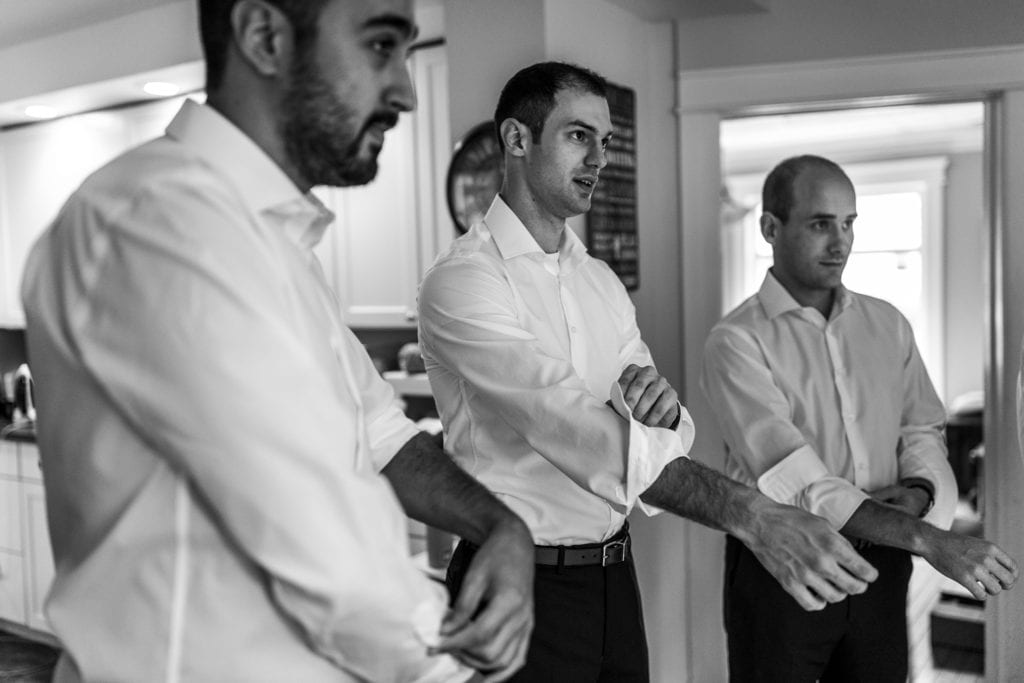 three groomsmen roll sleeves simultaneously