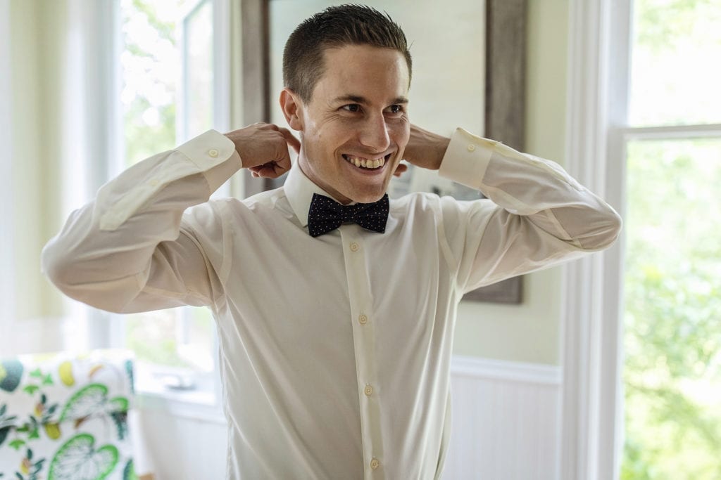 groom smiles while hooking fingers into collar