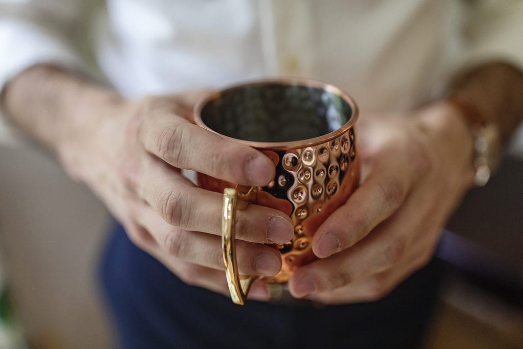 groom holds copper mug during wedding prep
