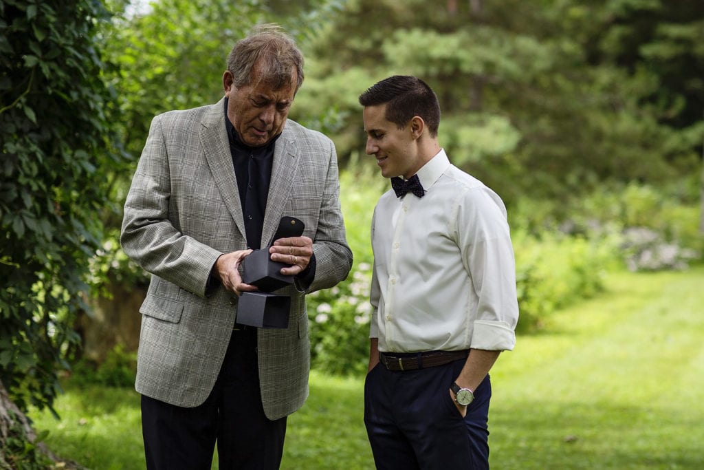 groom with father as father opens gift