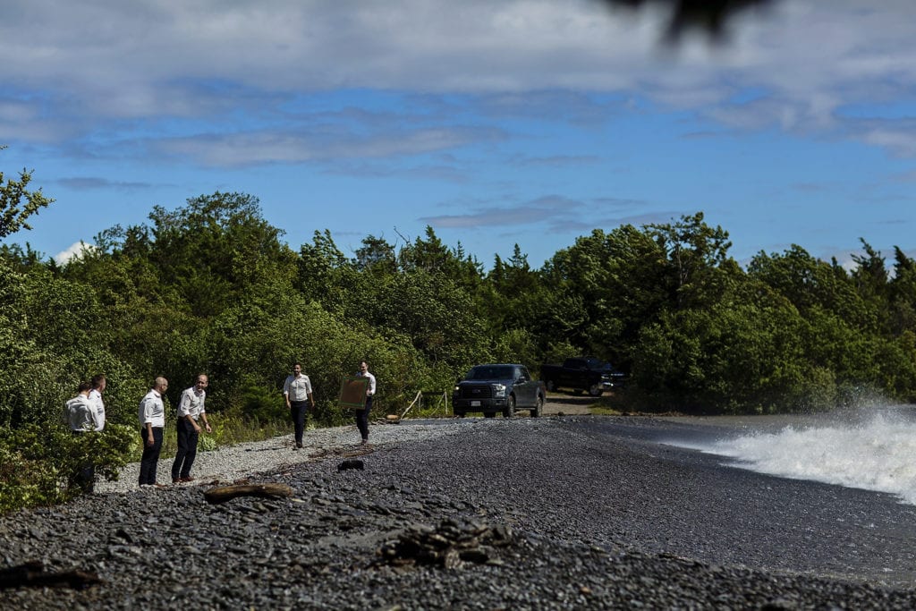 groomsmen and truck on shoreline as waves crash in