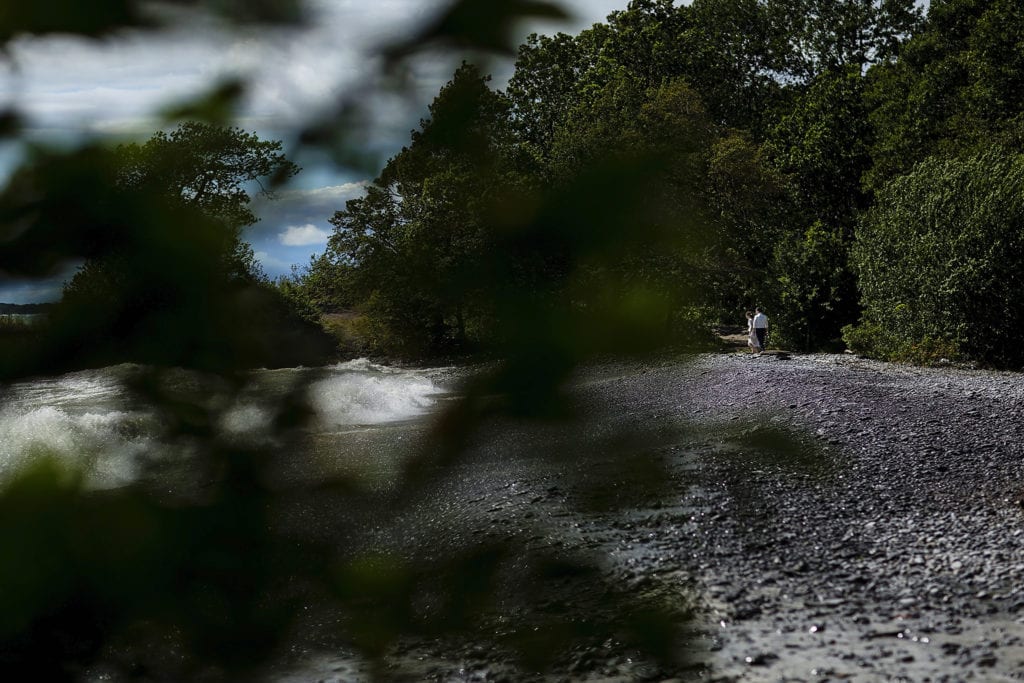 Bride and groom walk off down shoreline ahead of windy Point Petre wedding ceremony