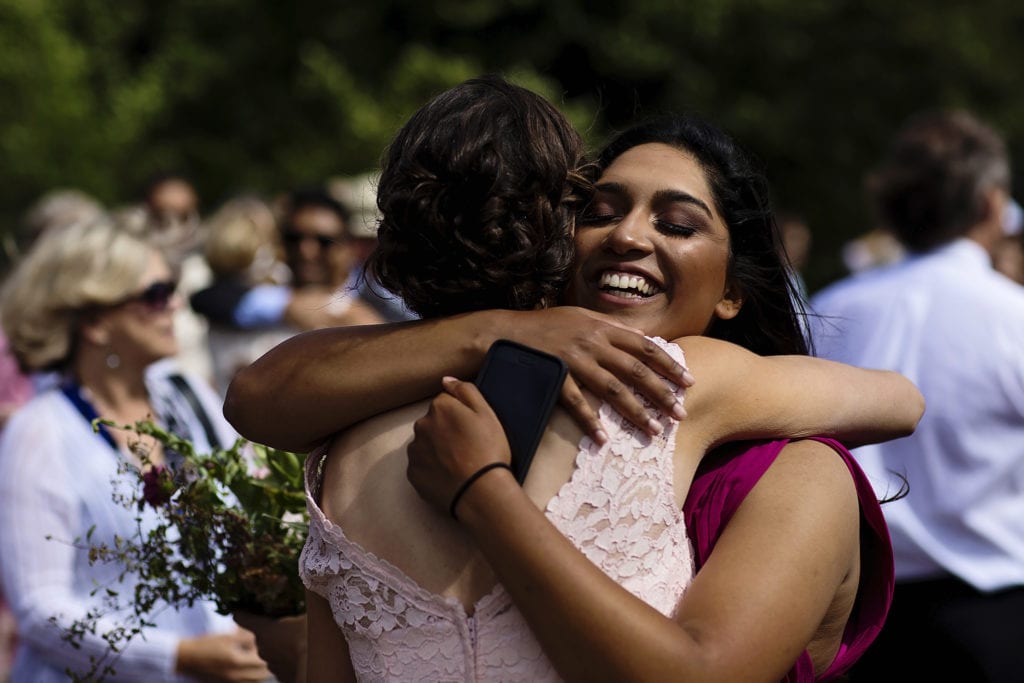 wedding guests in pink dresses hug tightly