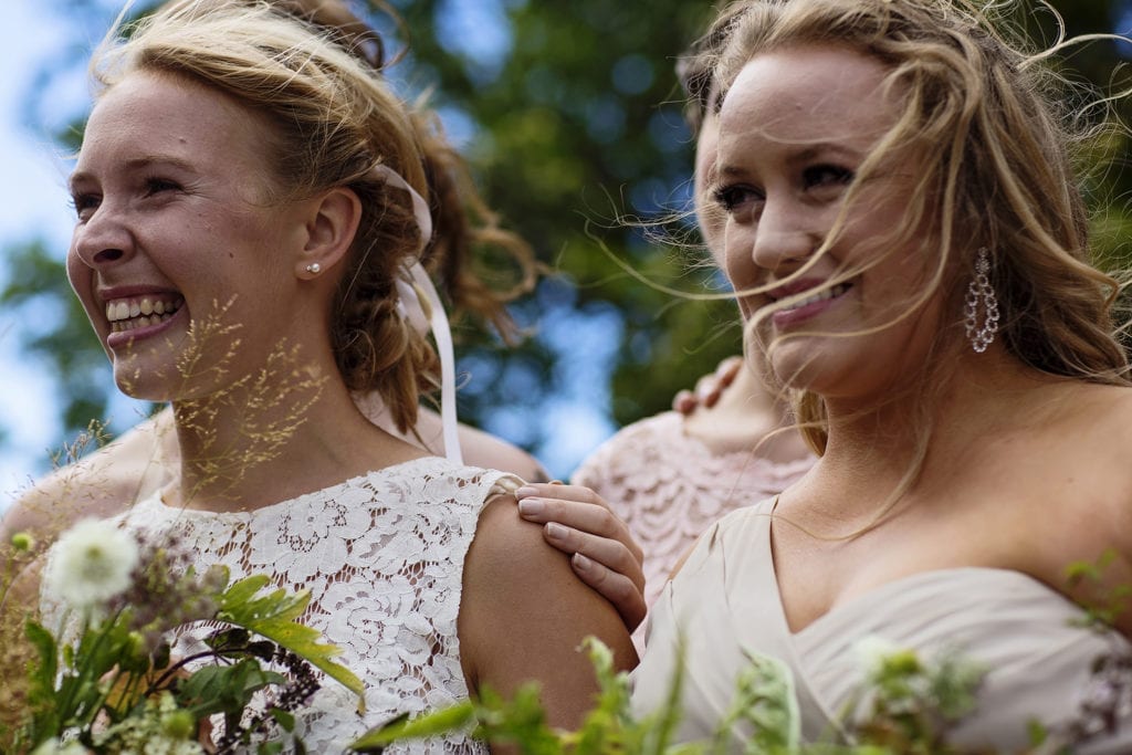 windblown bridesmaids smile during Point Petre wedding ceremony