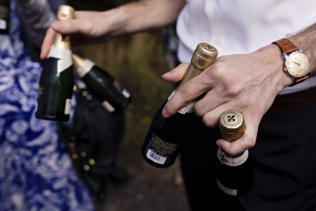 man's hands holding four small bottles of sparkling wine