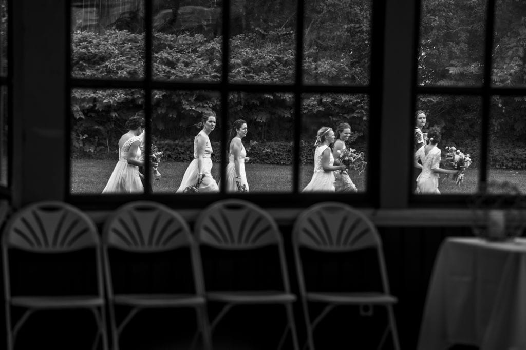 bridesmaids seen through window walking across lawn