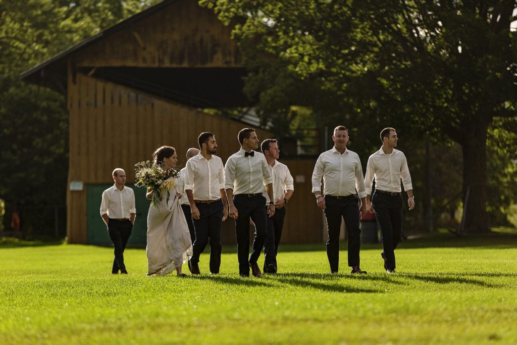 bride walks across lawn with groom and groomsmen
