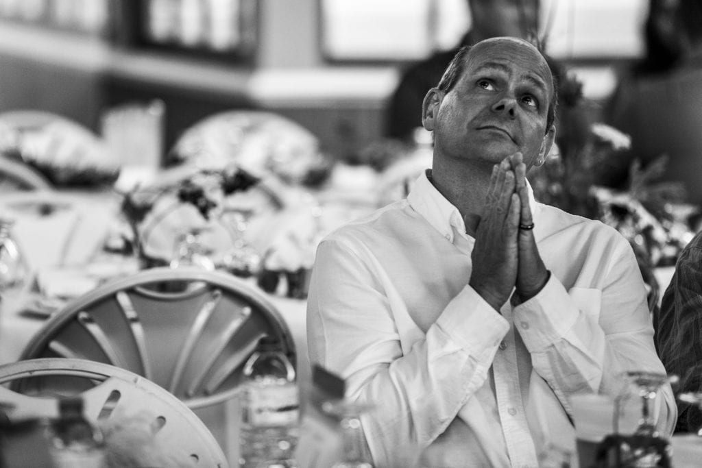 man clasps hands together in prayer and looks up