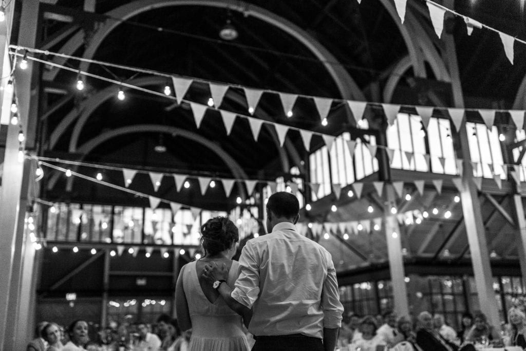Groom rests hand on wife's back as they deliver speech to wedding guests at Picton Crystal Palace