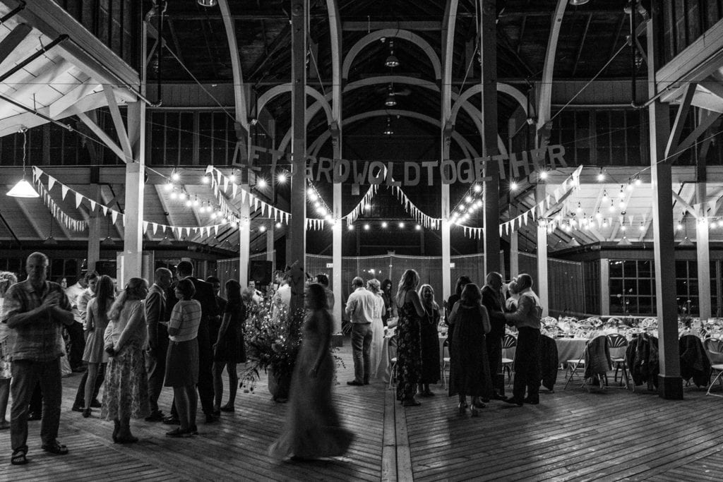 wedding guests stand under sign hung from Picton Crystal palace rafters saying let's grow old together