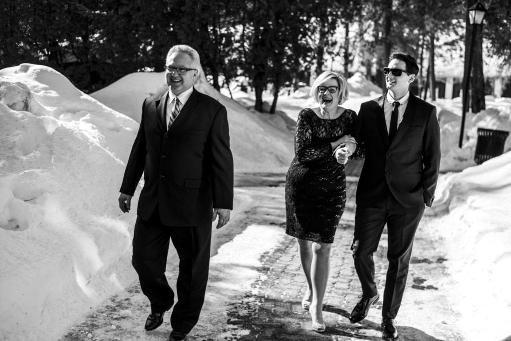 groom walks with mother and father in the snow