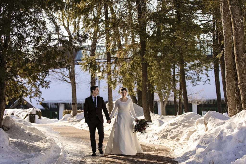 bride and groom walk together while holding hands