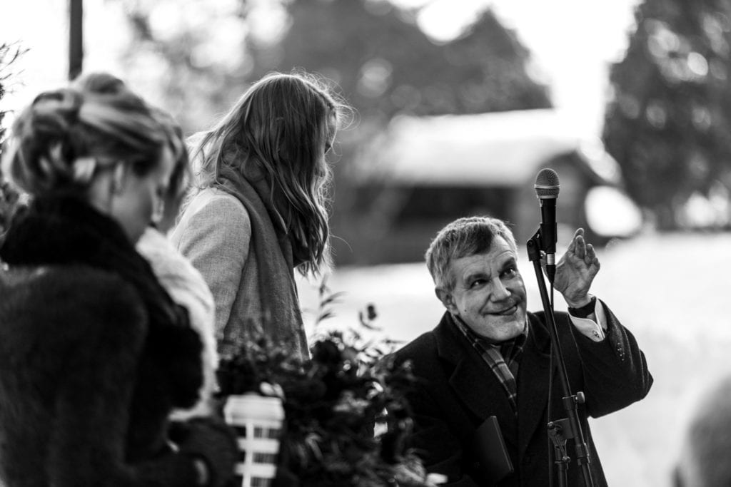 wedding officiant smiles wryly while lowering the microphone