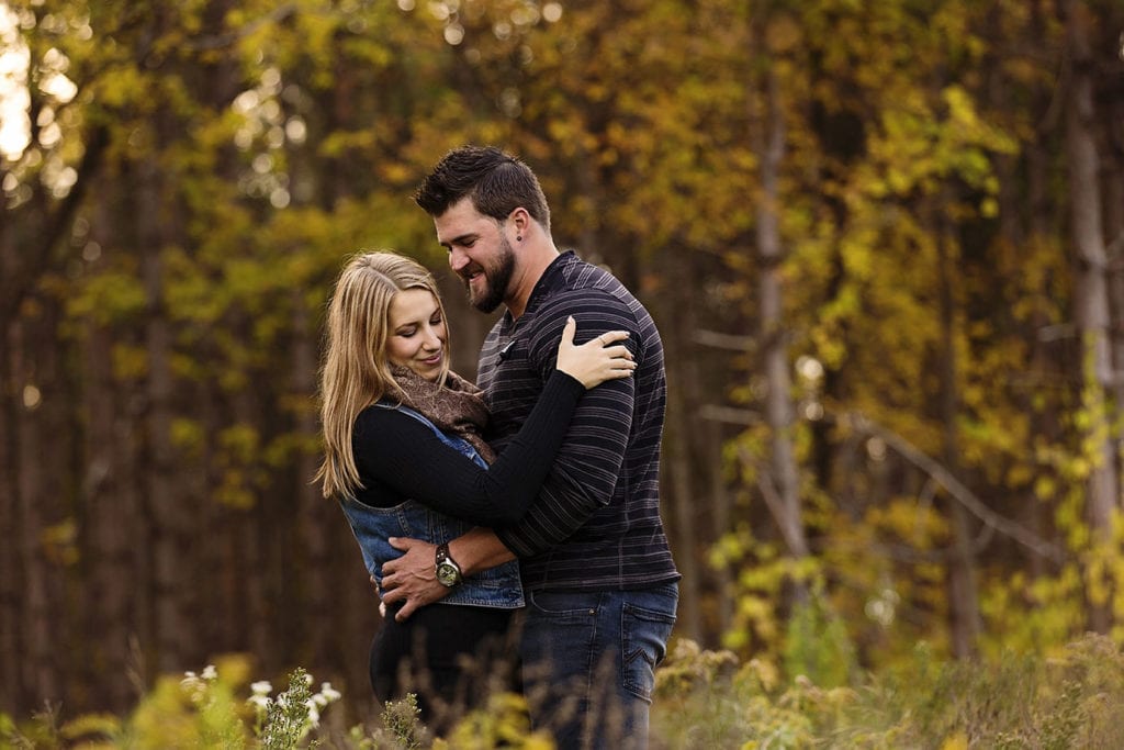 handsome young couple in fall forest during woodsy engagement shoot