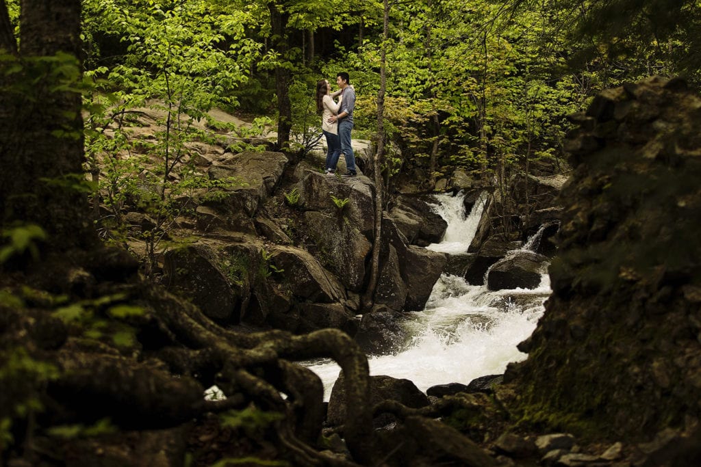 couple standing on hilltop beside waterfalls in Gatineau Park engagement session