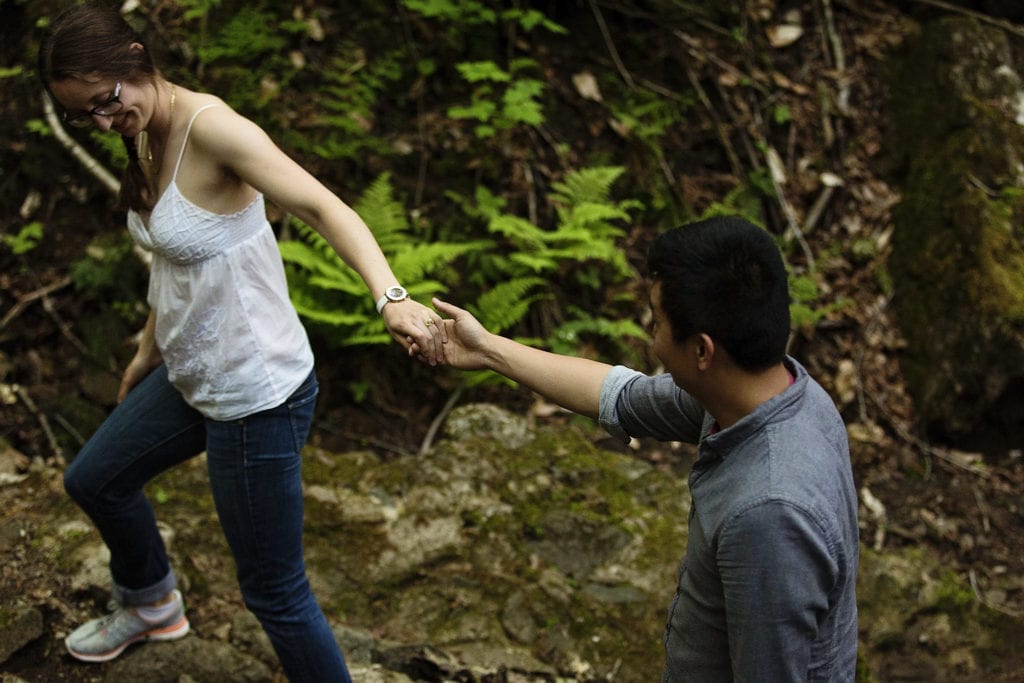 couple walking hand in hand through forest during Gatineau Park engagement session