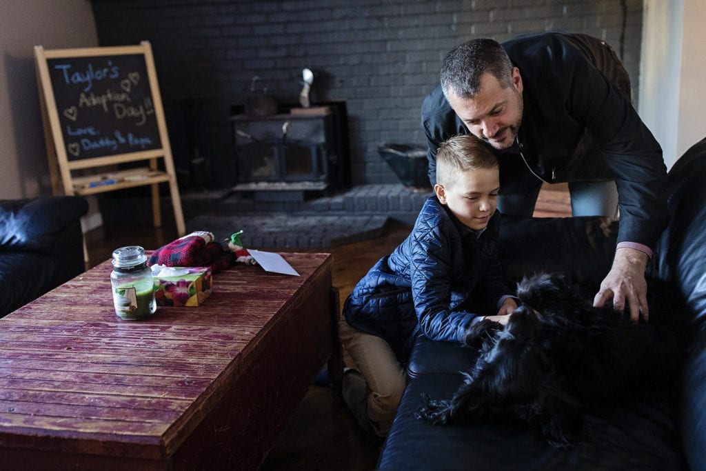 dad and son play with dog laying on couch before Adoption day in Cornwall