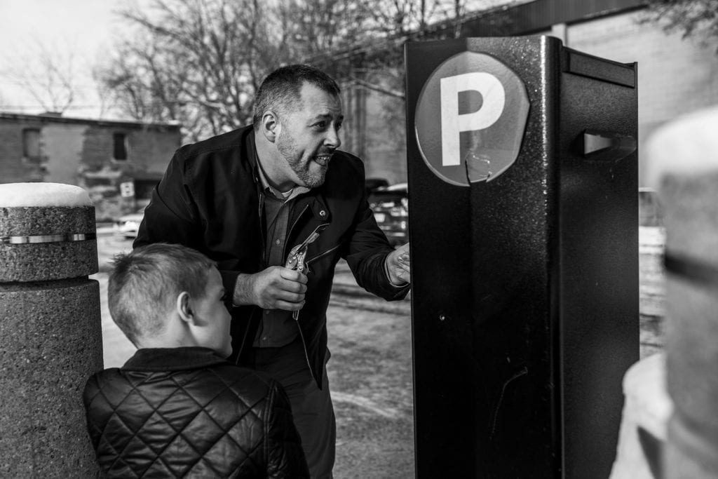 man pays for parking with credit card held by wrench while son looks on