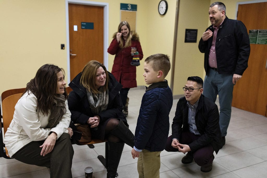 family are all smiles with young boy while waiting in cornwall courthouse on adoption day