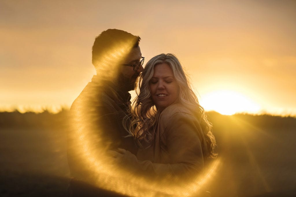 couple embracing in field with brilliant sun flare at Williamstown Engagement Session