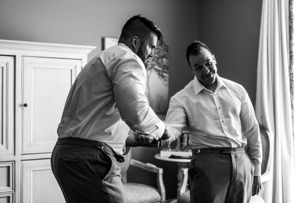 man makes funny face as he's helped with cufflink