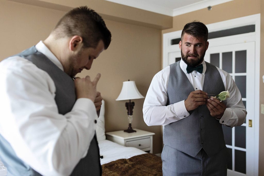 groom makes face while figuring out how to pin boutonniere