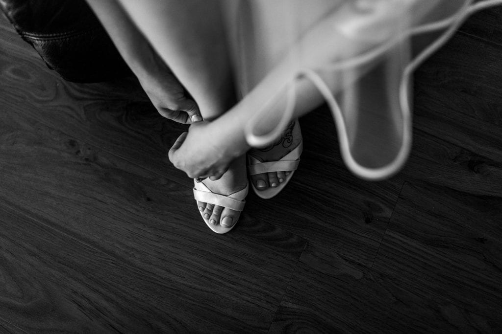 bride fastens strappy shoes