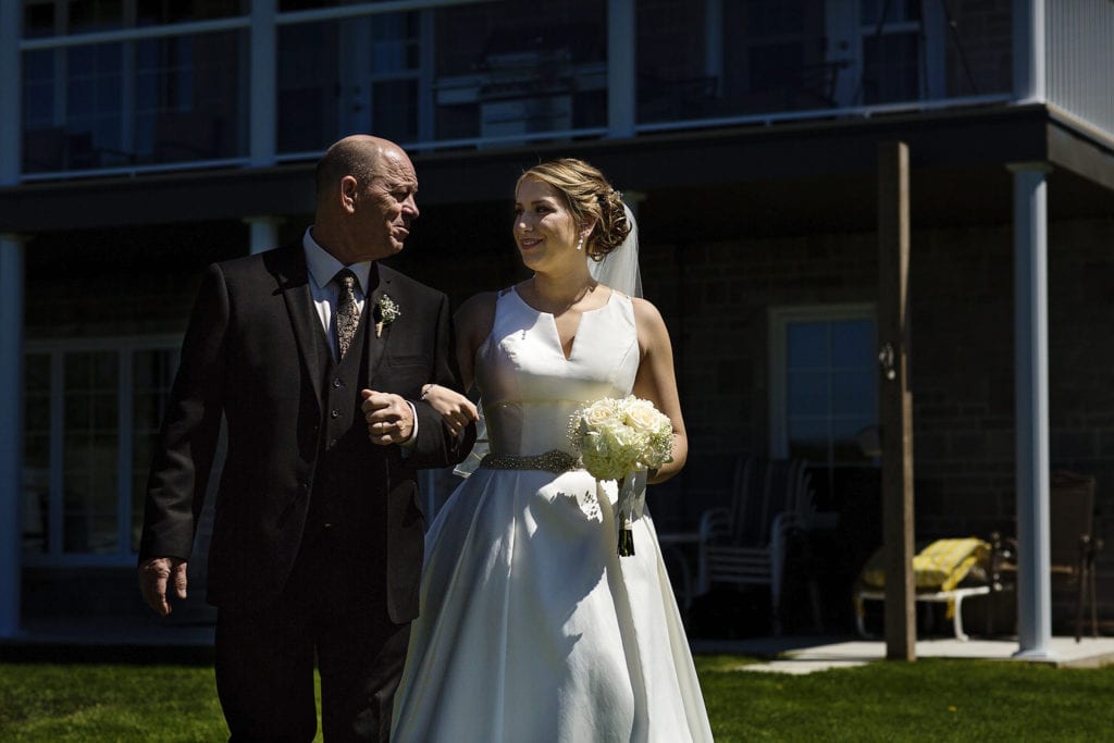 bride and father look at each other as they walk towards wedding ceremony