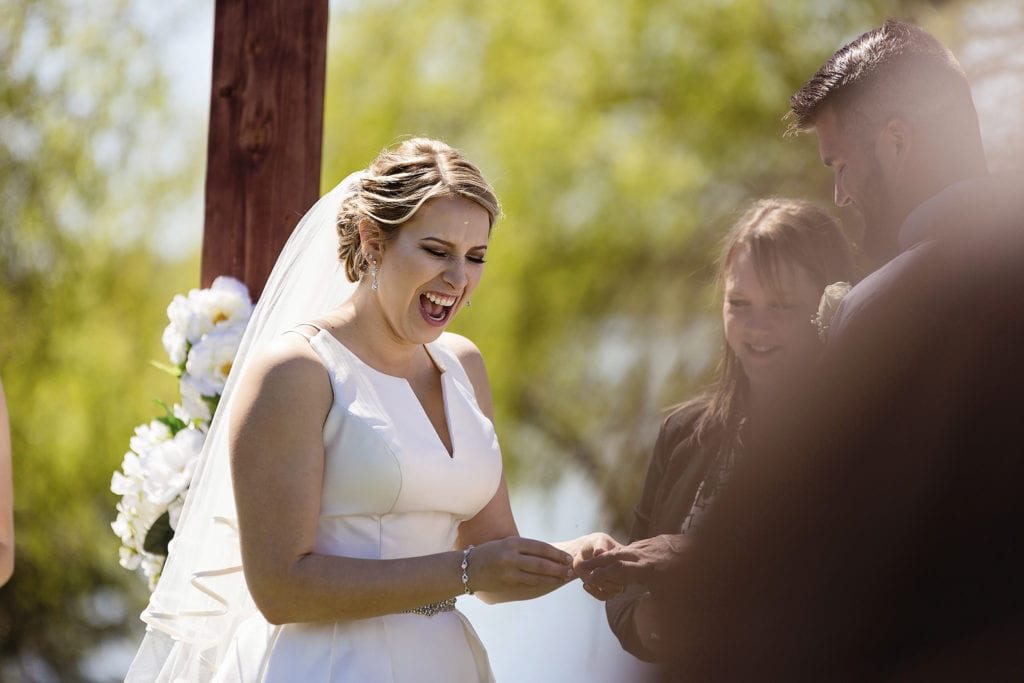 bride looks super excited as she places ring on groom's finger during Plantagenet wedding ceremony