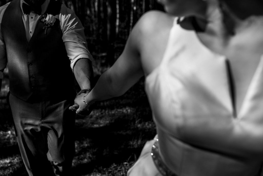 close up shot of bride and groom walking holding hands as bride leads the way