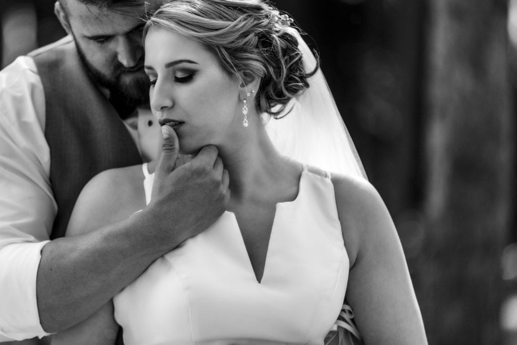 groom holds bride close and touches thumb to her lip