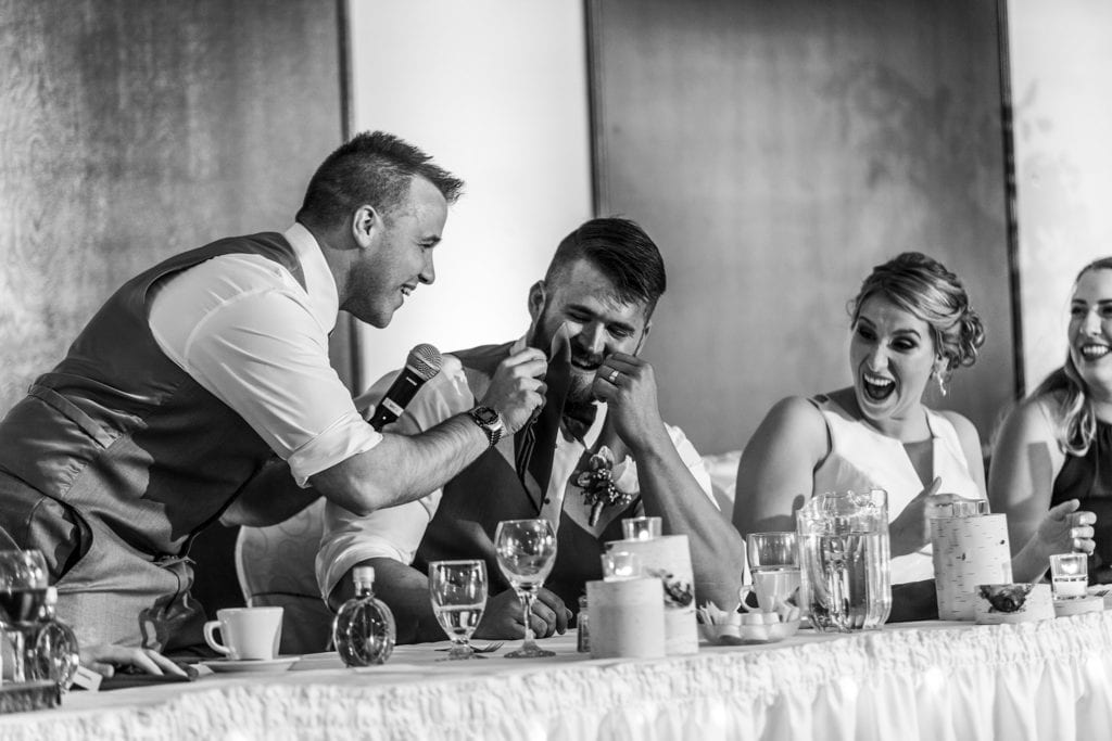 groomsman pretends to wipe groom's tear while bride looks shocked