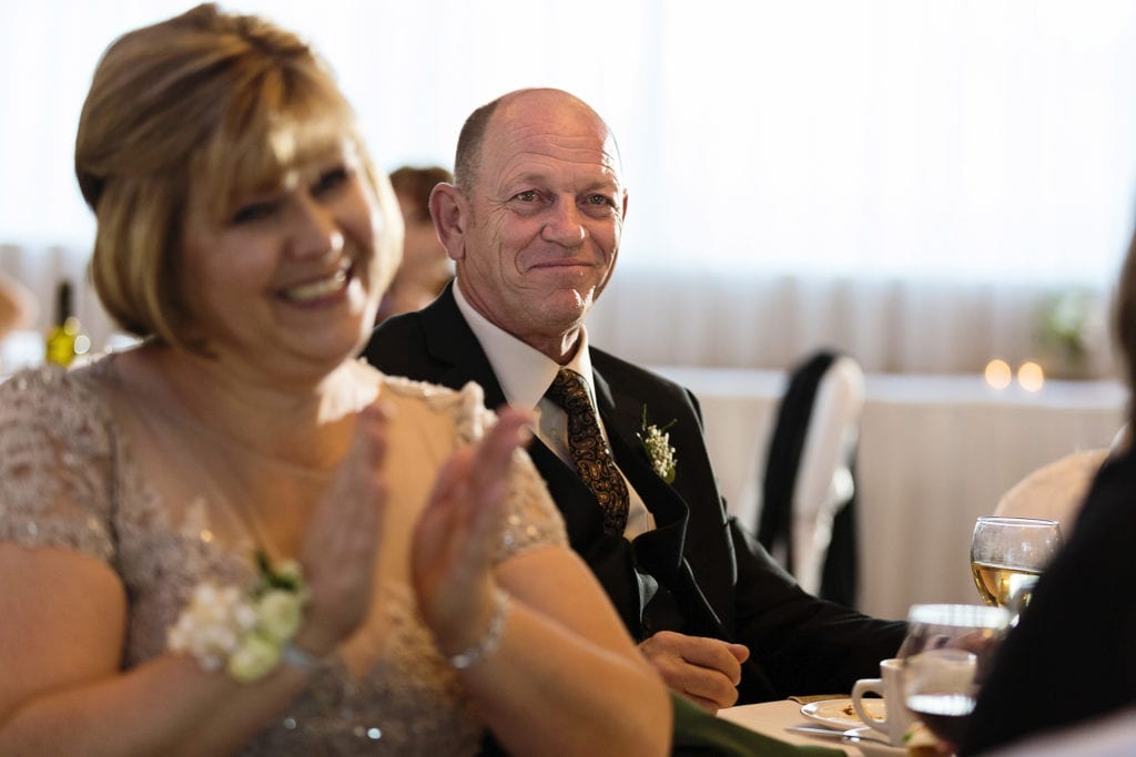 mother of the bride claps while father looks on and smiles