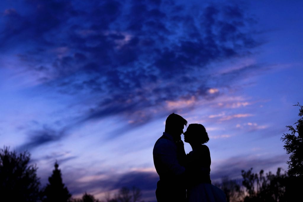 bride and groom silhouetted against vibrant blue sky