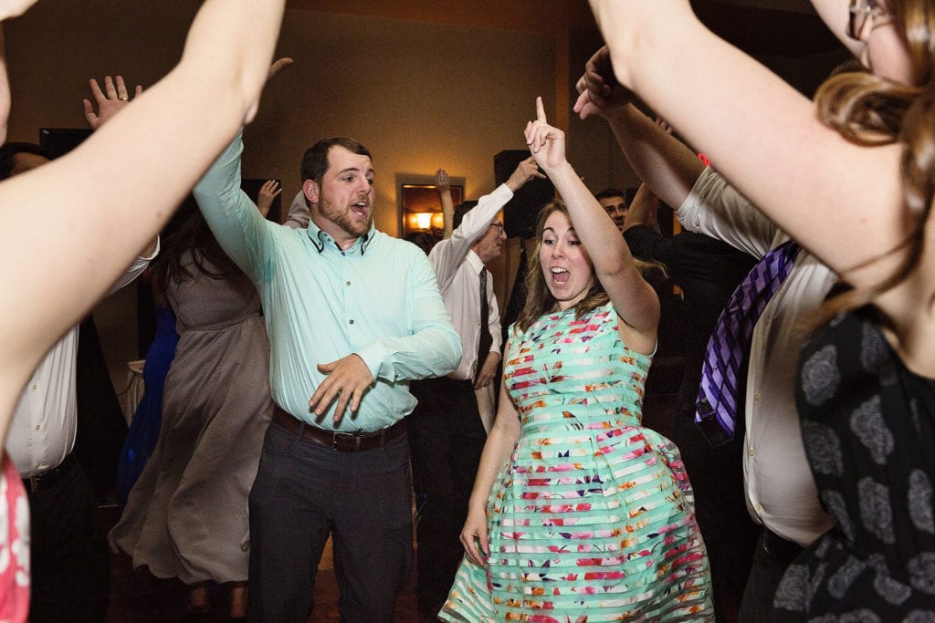 wedding guests in matching turquoise dance with arms raised