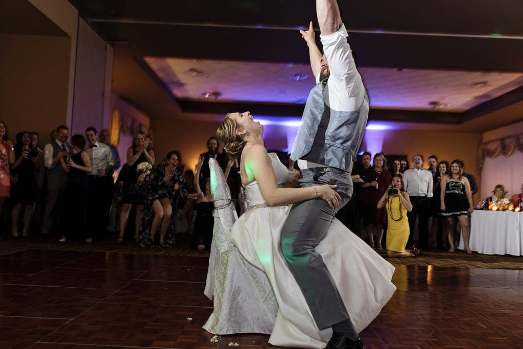 groom straddles seated bride as she throws her head back and laughs