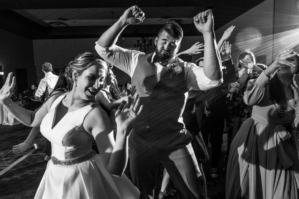 groom dances with arms raised behind bride during Rockland wedding celebration