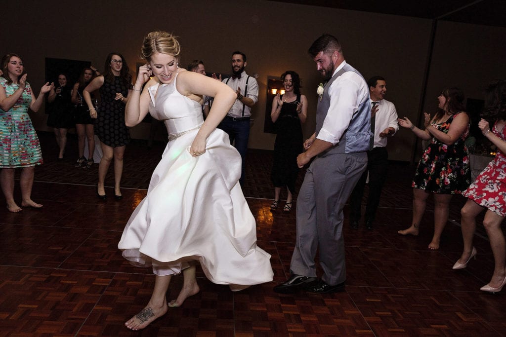 bride and groom dance together energetically while guests circle them