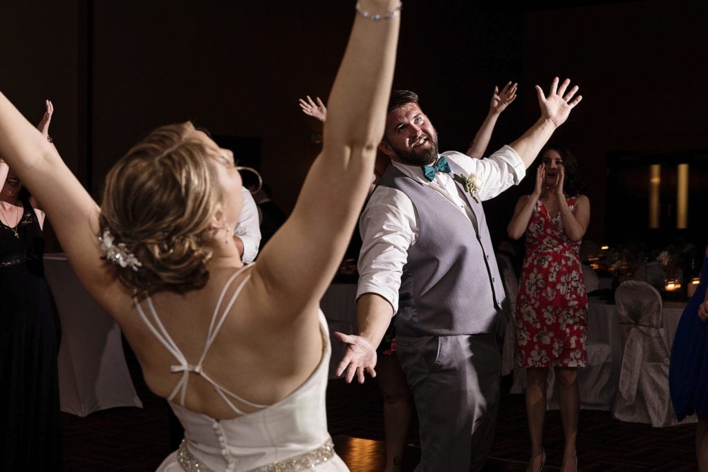 bride and groom dance with arms up