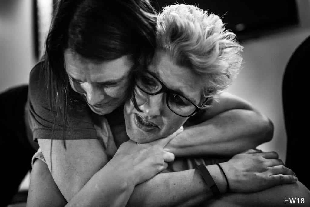 women hug while one cries